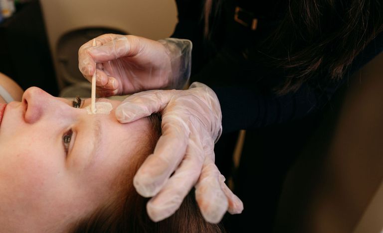Esthetician applying wax for an eyebrow shaping at Alpha Chiropractic