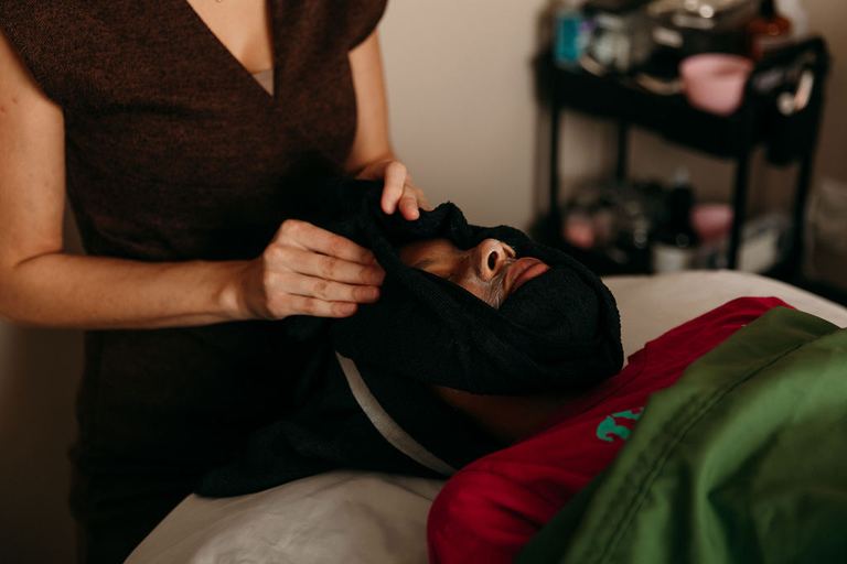 Esthetician placing a warm towel during a facial
